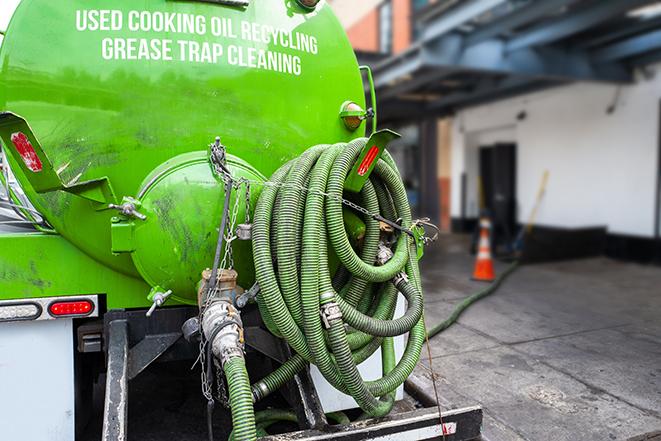 worker pumping grease trap at commercial kitchen in Billerica